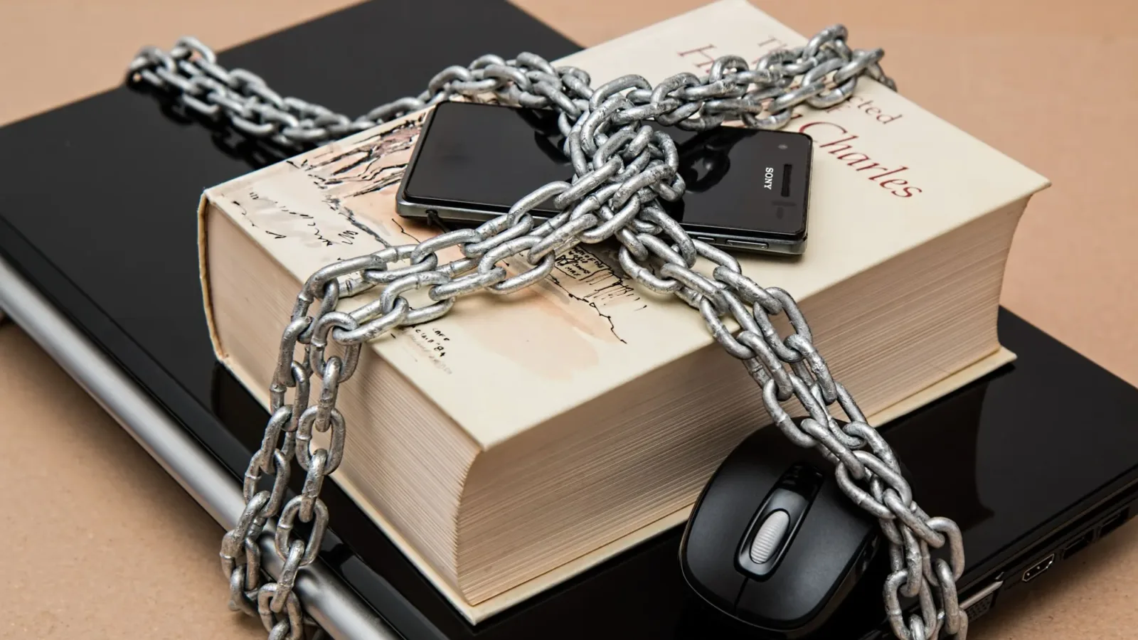 Chain-locked book, phone, and laptop symbolizing digital and intellectual security.