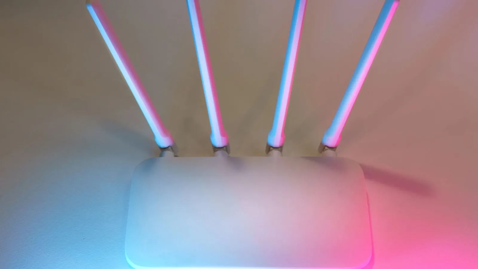 Sleek white wireless router with four antennas emitting soft blue and pink light.