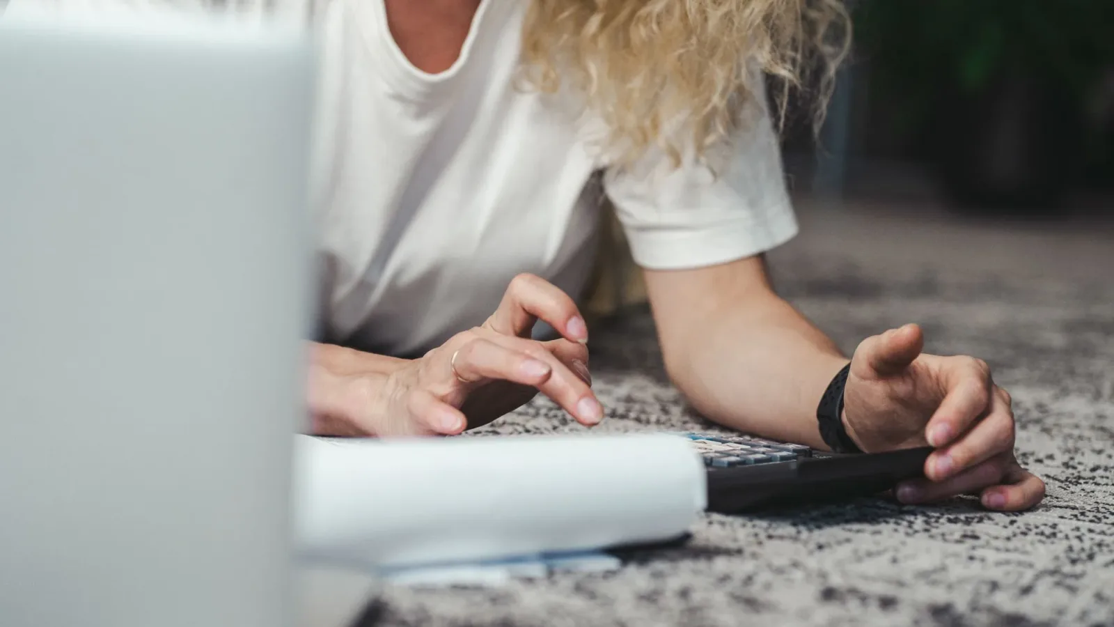 A woman engages in budget planning using a calculator on a comfortable carpeted floor.