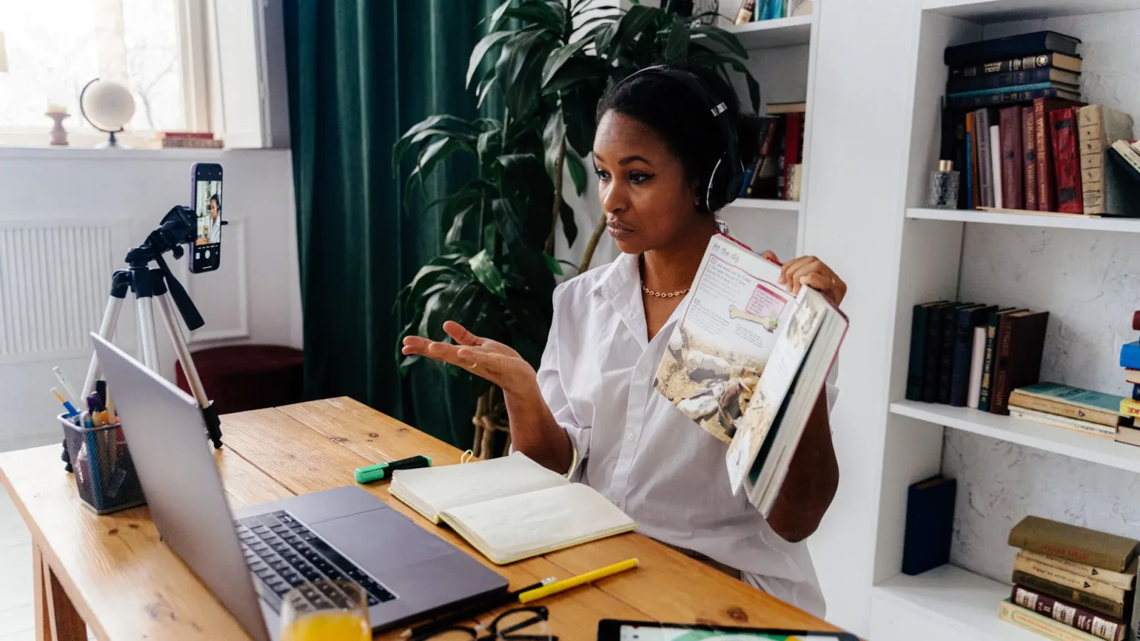 Woman conducting online teaching session at home with laptop and books.