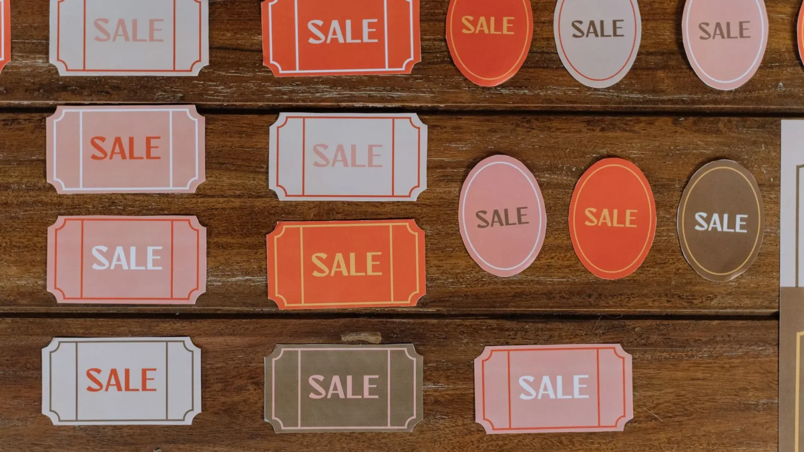 Various sale tags on a wooden surface ideal for retail marketing and promotions.